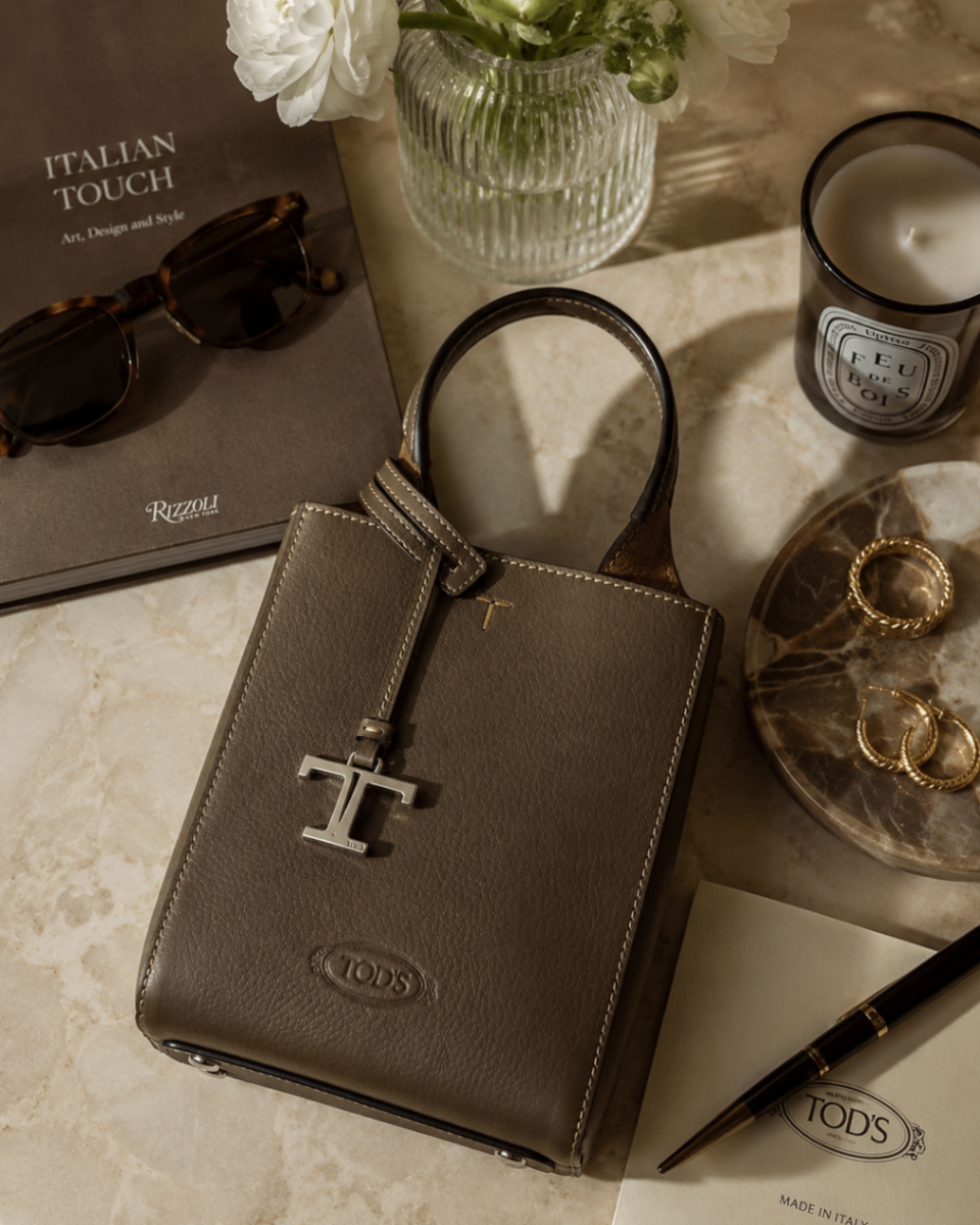 Taupe leather mini tote styled on marble with sunglasses, candle and gold jewellery